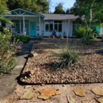 An front image of the home with a xeriscaped yard of rocks and drought tolerant plants.