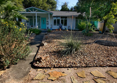 An front image of the home with a xeriscaped yard of rocks and drought tolerant plants.