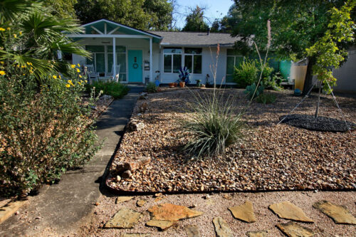 An front image of the home with a xeriscaped yard of rocks and drought tolerant plants.