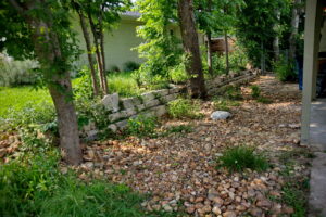 A river rock pathway leads to another bed of pollinators.