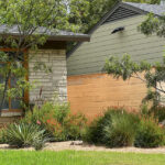 This is an image showing one of the beds near the left of the house. You'll find mesquite trees, coral yucca, red sage, and purple fountain grass planted in beds of crushed granite.